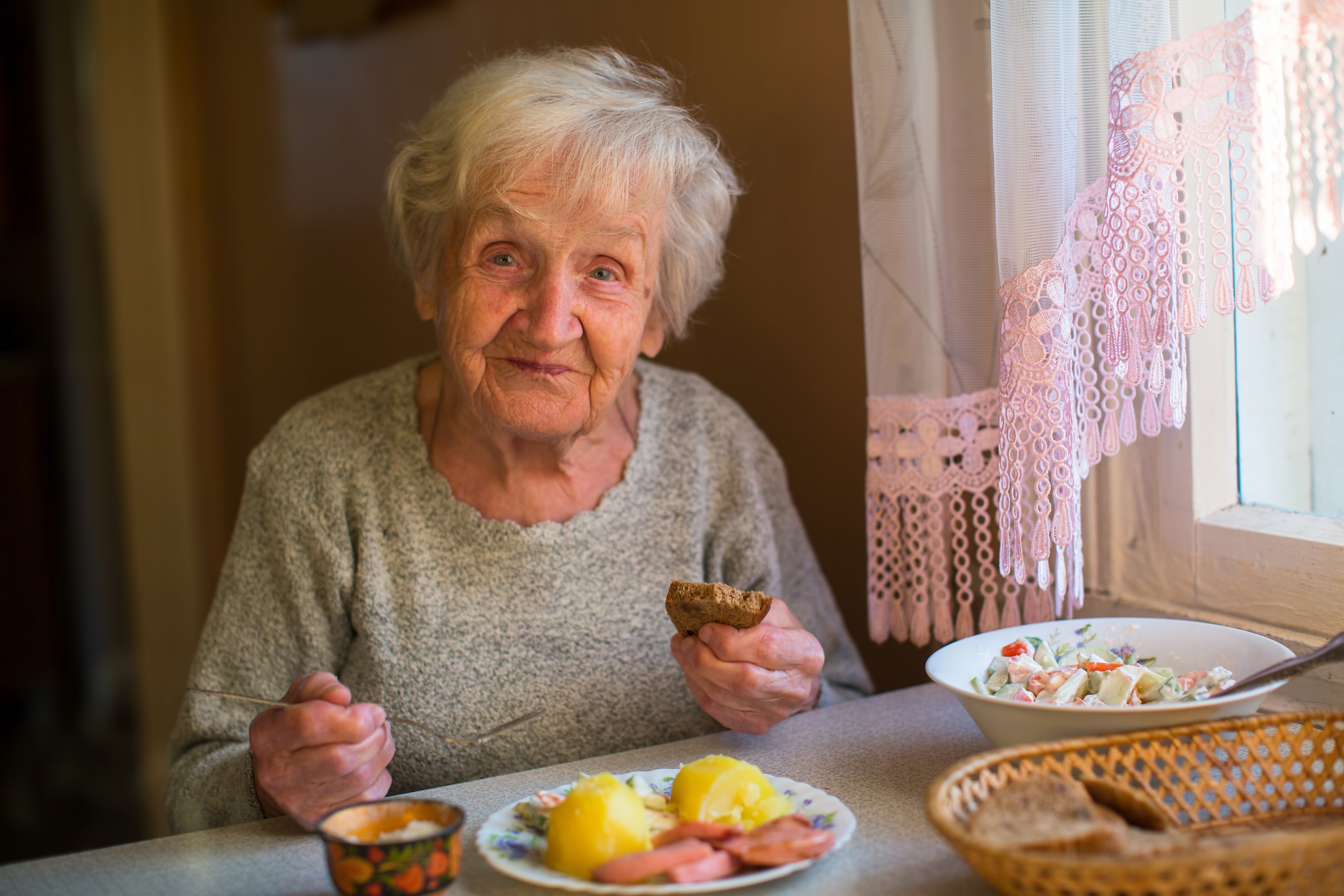 En äldre dam som ler, sittande vid ett dukat bord